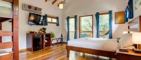 A bedroom with a wooden bed, a ceiling fan, a TV, and a window with curtains.