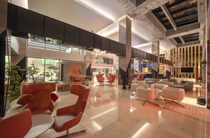 A spacious lobby with modern seating, a staircase, and a bar area. - Holiday Inn Kayseri - Duvenonu by IHG (Kocasinan)