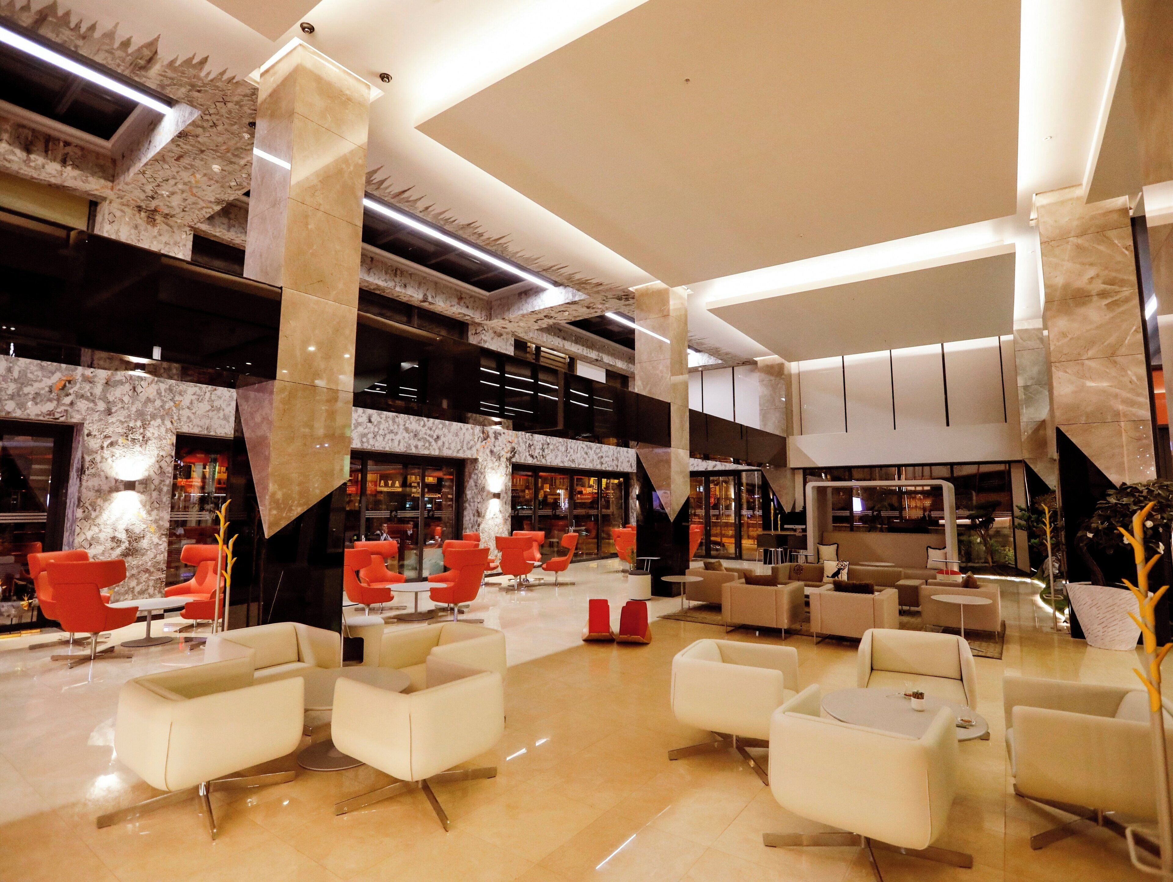 A spacious lobby with multiple seating areas, a central staircase, and a modern design.