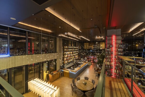 Een modern interieur met een bar, zitplaatsen en boekenkasten.