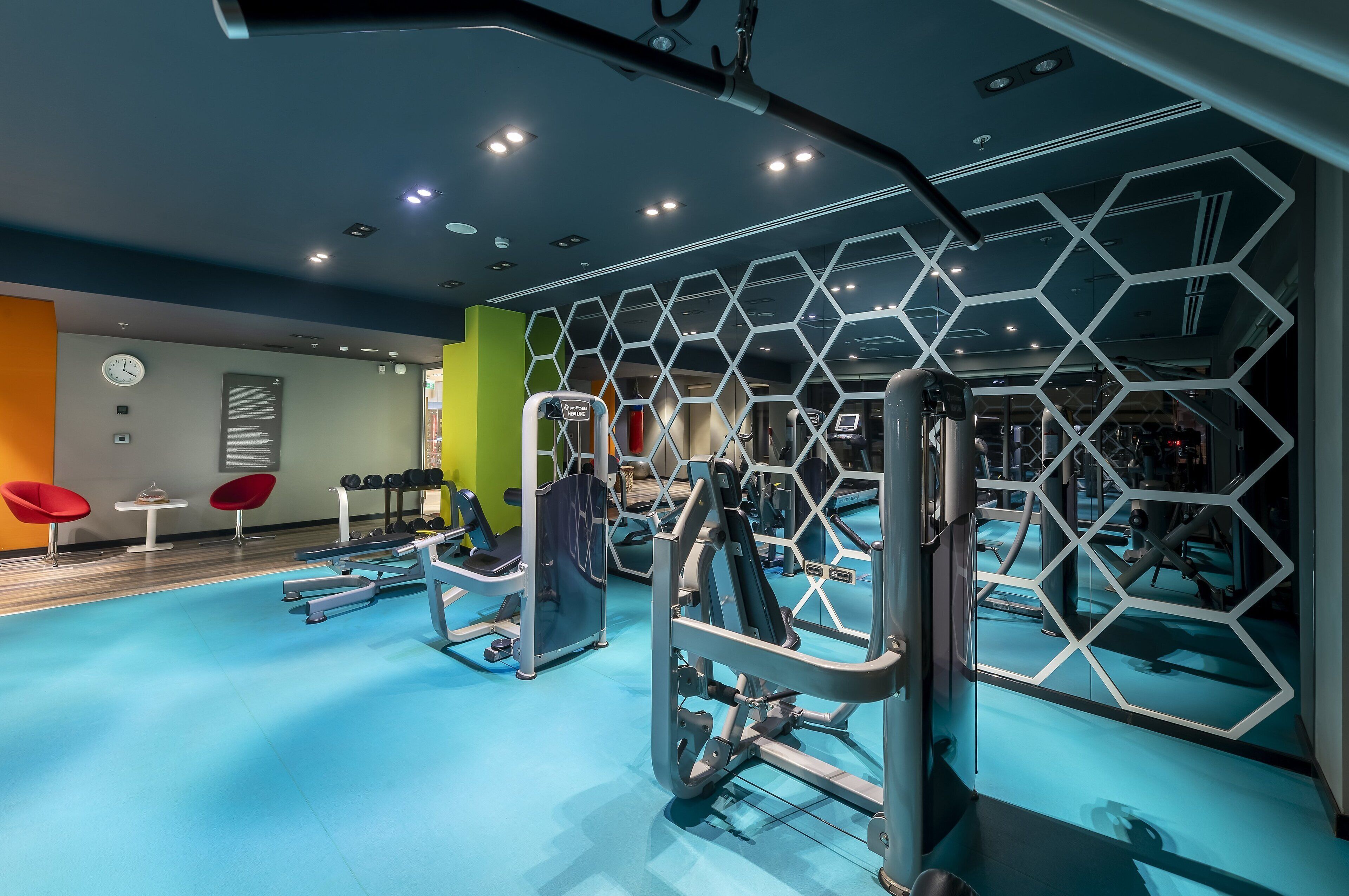 Una palestra moderna con attrezzature per esercizi, un pavimento blu e un design geometrico alle pareti.