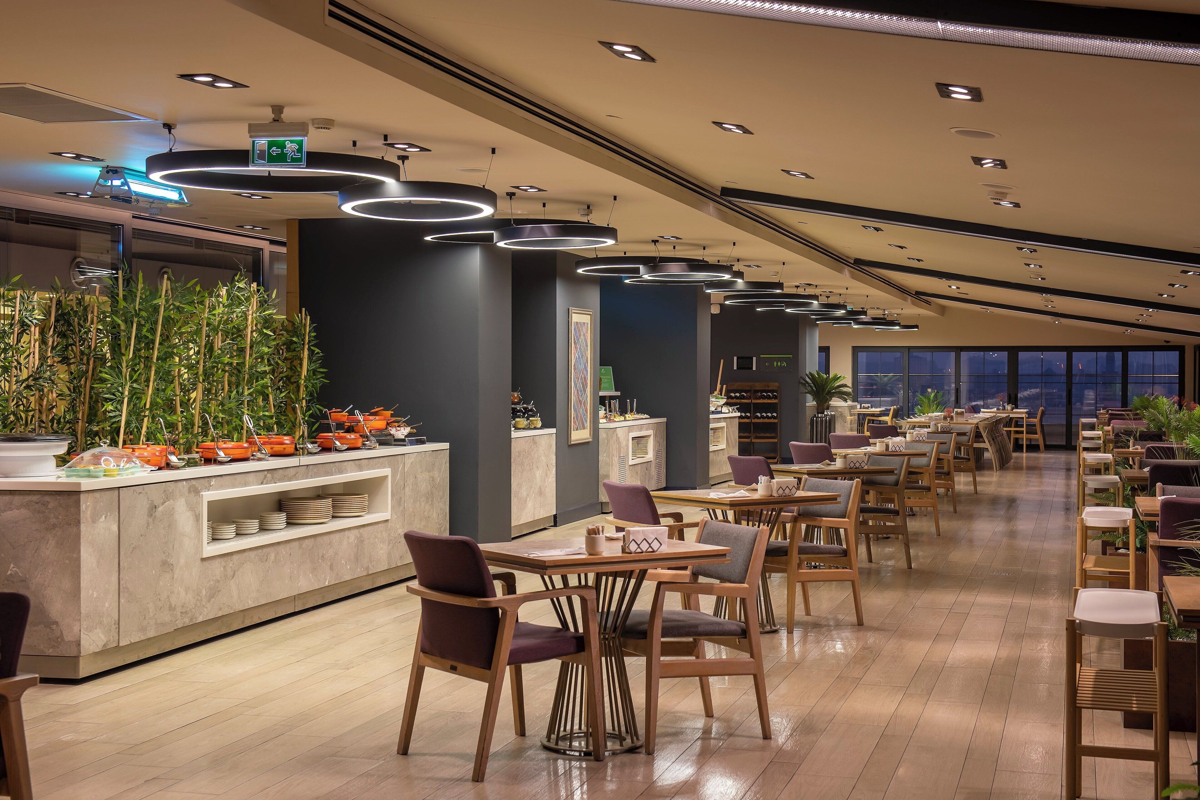 Un restaurante moderno con una barra larga, sillas de madera y una variedad de platos expuestos.