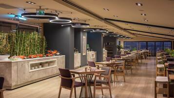 Un restaurante moderno con una barra larga, sillas de madera y una variedad de platos expuestos.