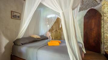 A bed with a canopy, a wooden door, and a stone wall.