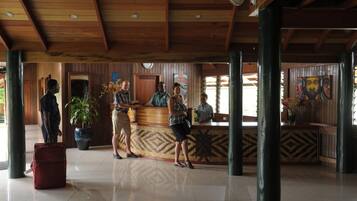 A reception area with a wooden ceiling, a reception desk, and a large potted plant.