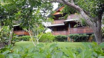 A traditional wooden building with multiple balconies, surrounded by lush greenery.