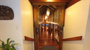 A wooden staircase leading to a room with a chandelier and patterned walls.