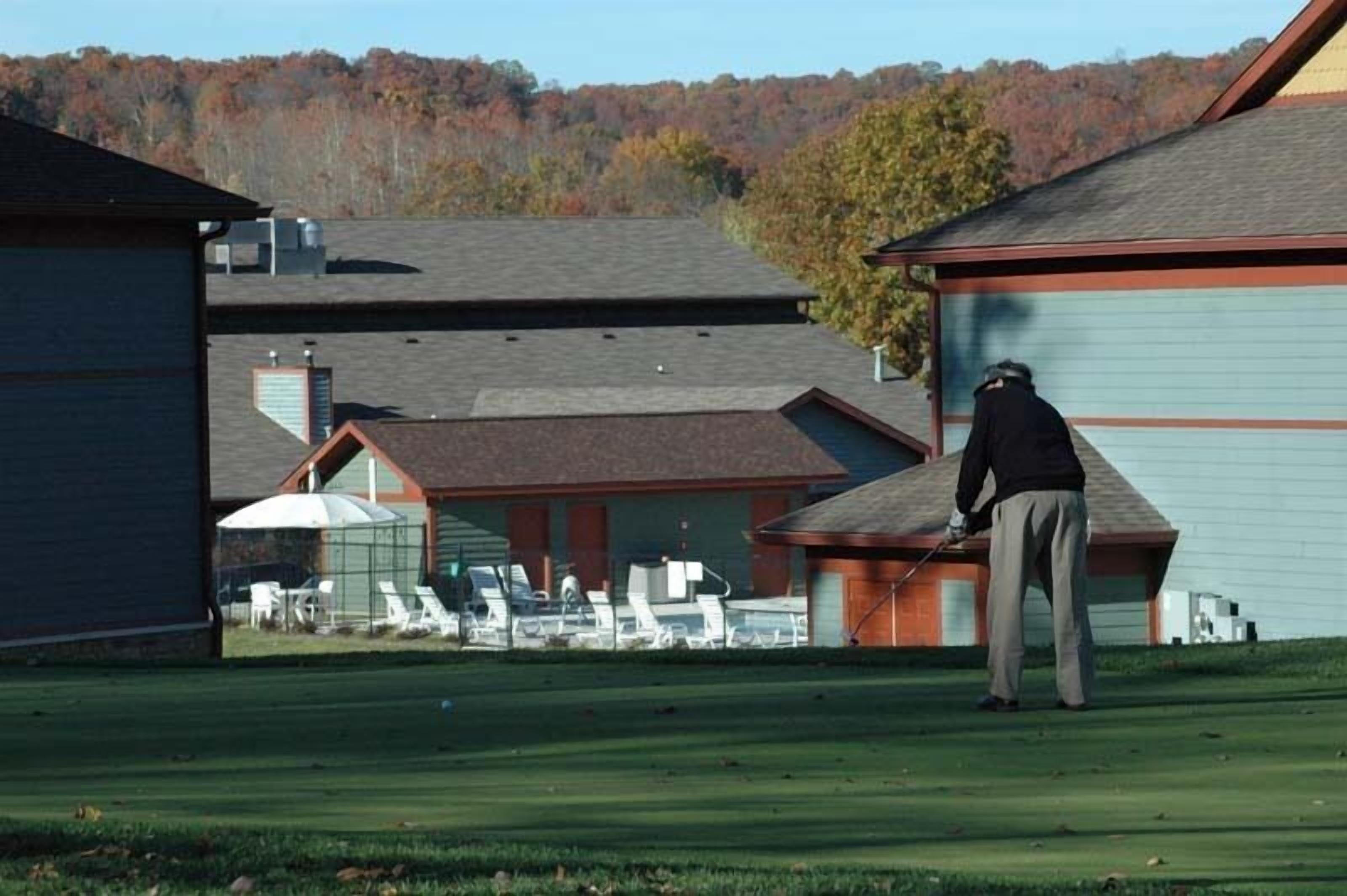 A golf course with a clubhouse, a covered seating area, and a person playing golf.