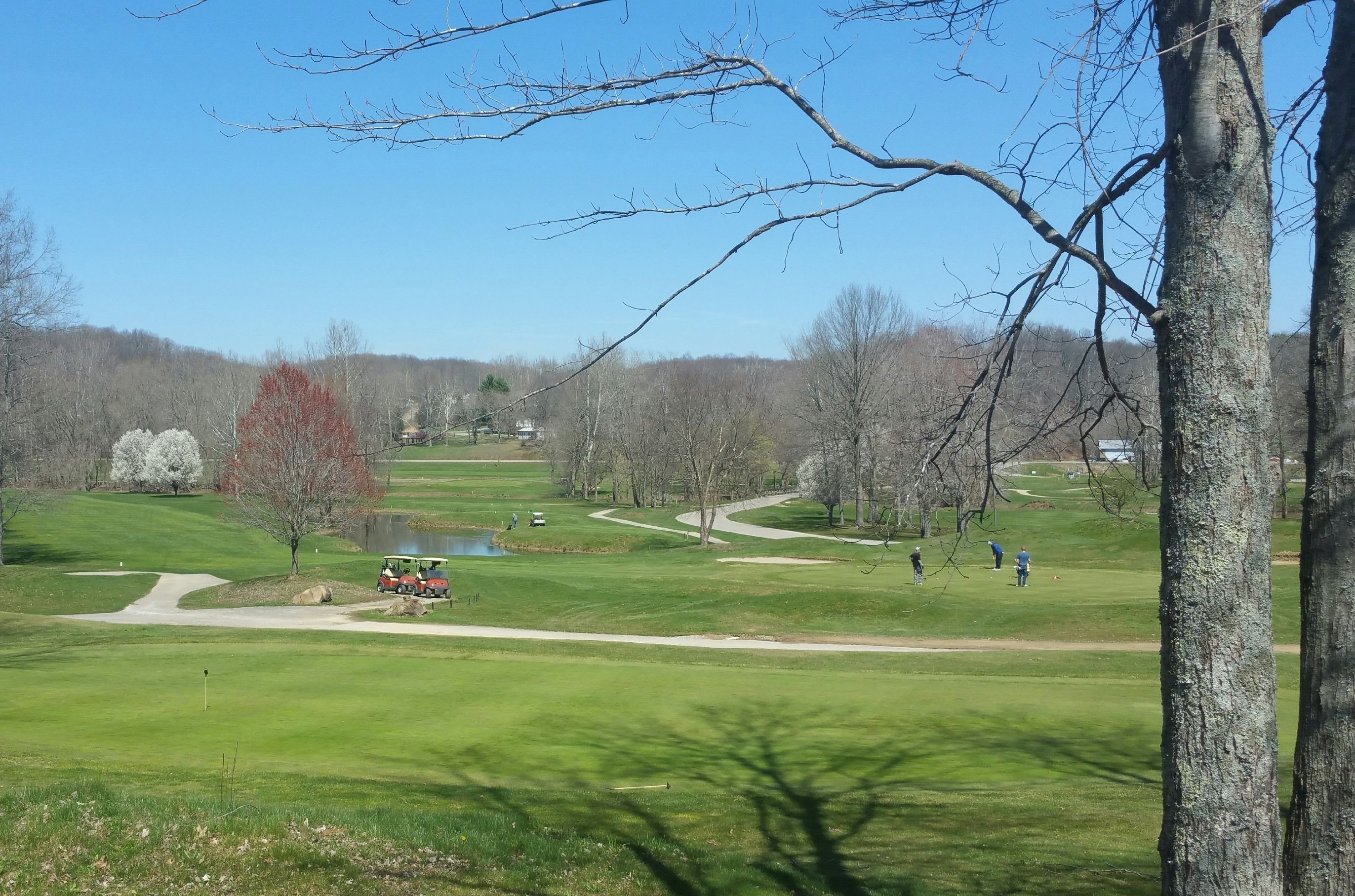 Un parcours de golf avec un chemin bien défini, des arbres et un bâtiment situé au loin.