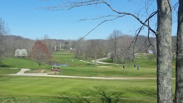 Un parcours de golf avec un chemin bien défini, des arbres et un bâtiment situé au loin.