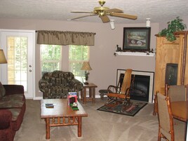 Una sala de estar con ventilador de techo, chimenea y televisor.