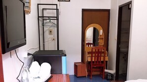 A room with a bed, a wooden table with a chair, a TV, an air conditioner, and a small mirror. - Palm House white building (Mae Hong Son)