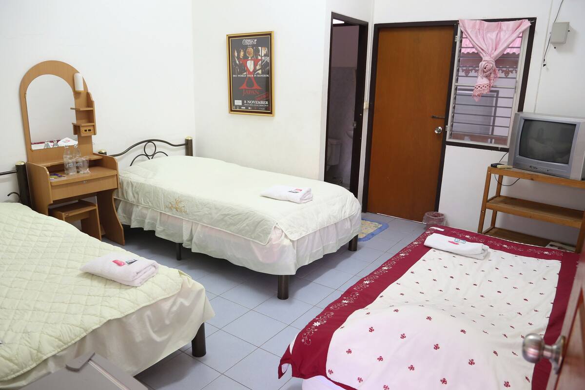A hotel room with two single beds, a wooden desk with a mirror, a television on a stand, and a poster on the wall.