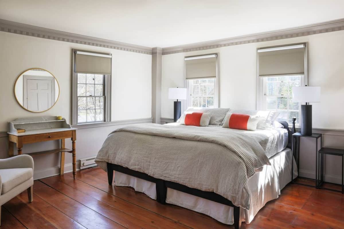 A bedroom with a bed, bedside tables, a desk, and a chair.