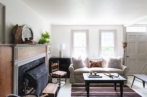 Una sala de estar con chimenea, un conjunto de sofás, una mesa de centro y una lámpara.