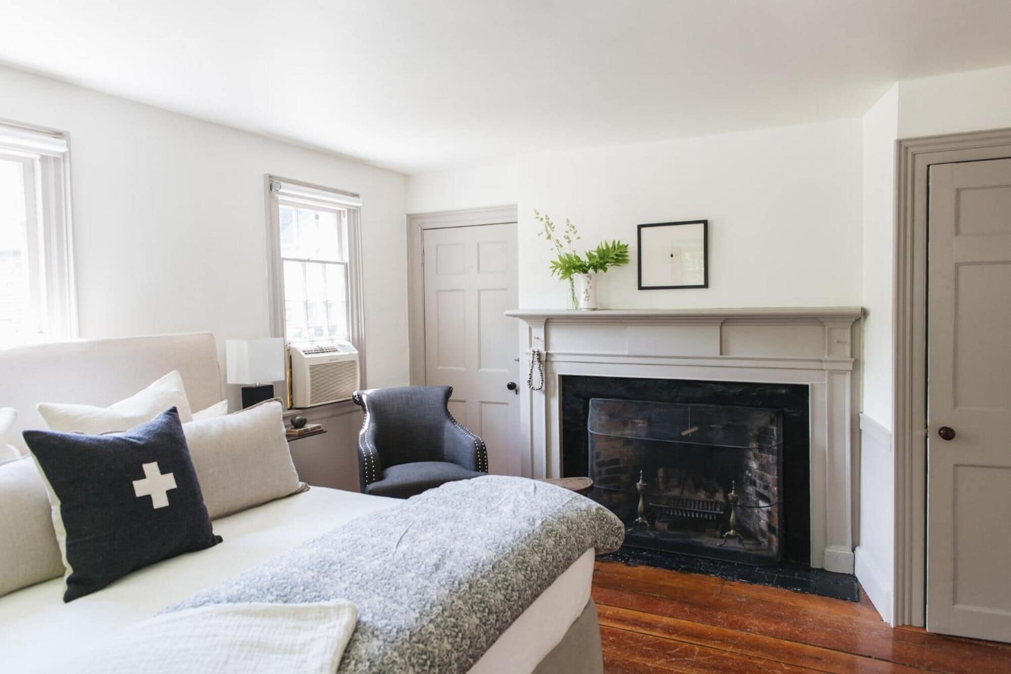 Un dormitorio con cama, chimenea, ventana y puerta.