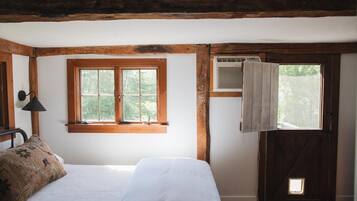 A bedroom with a bed, a window, and a door with an air conditioning unit.