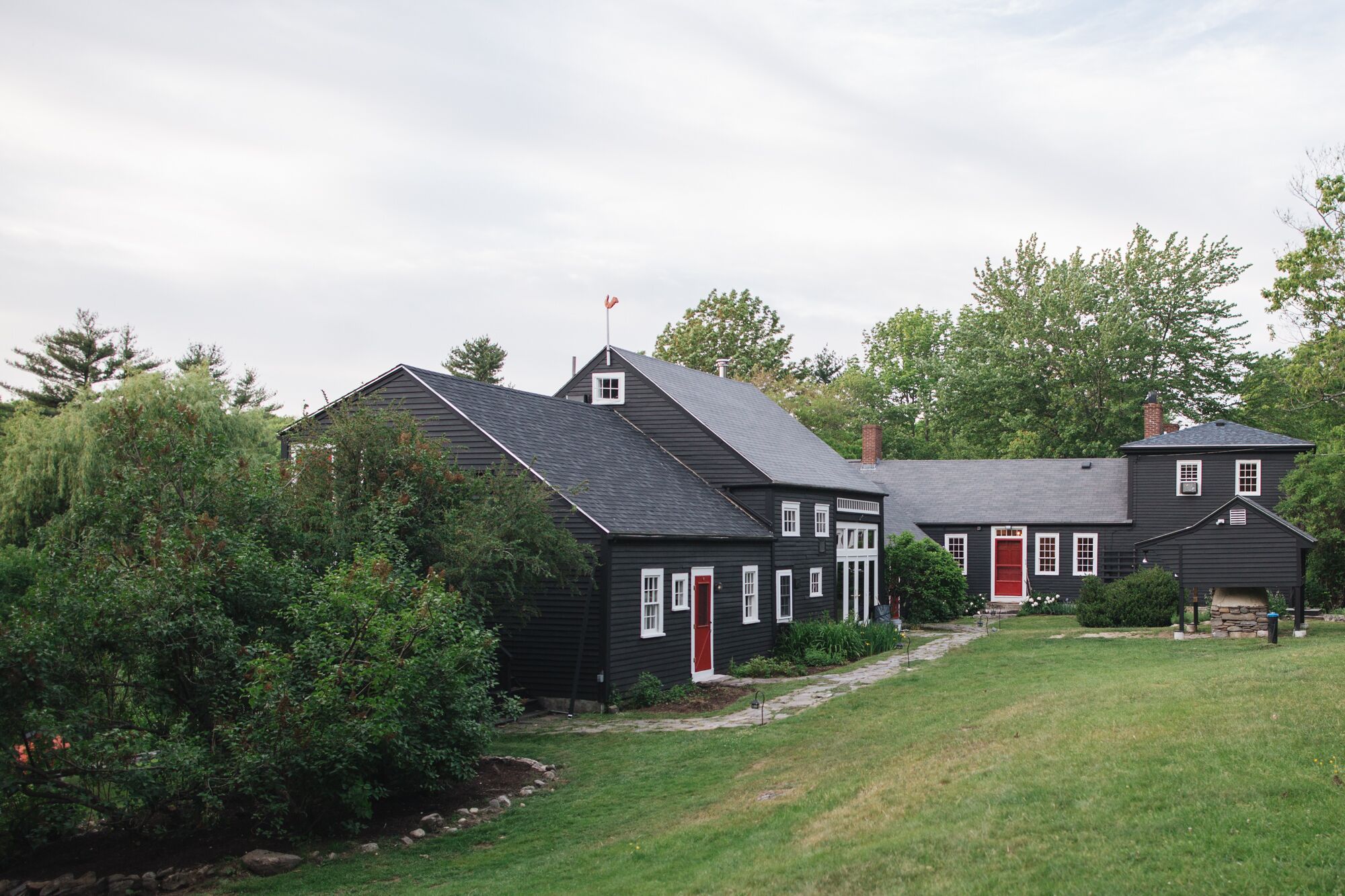 A two-story house with a red door, surrounded by a well-maintained lawn and trees.