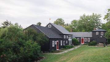 A two-story house with a red door, surrounded by a well-maintained lawn and trees.