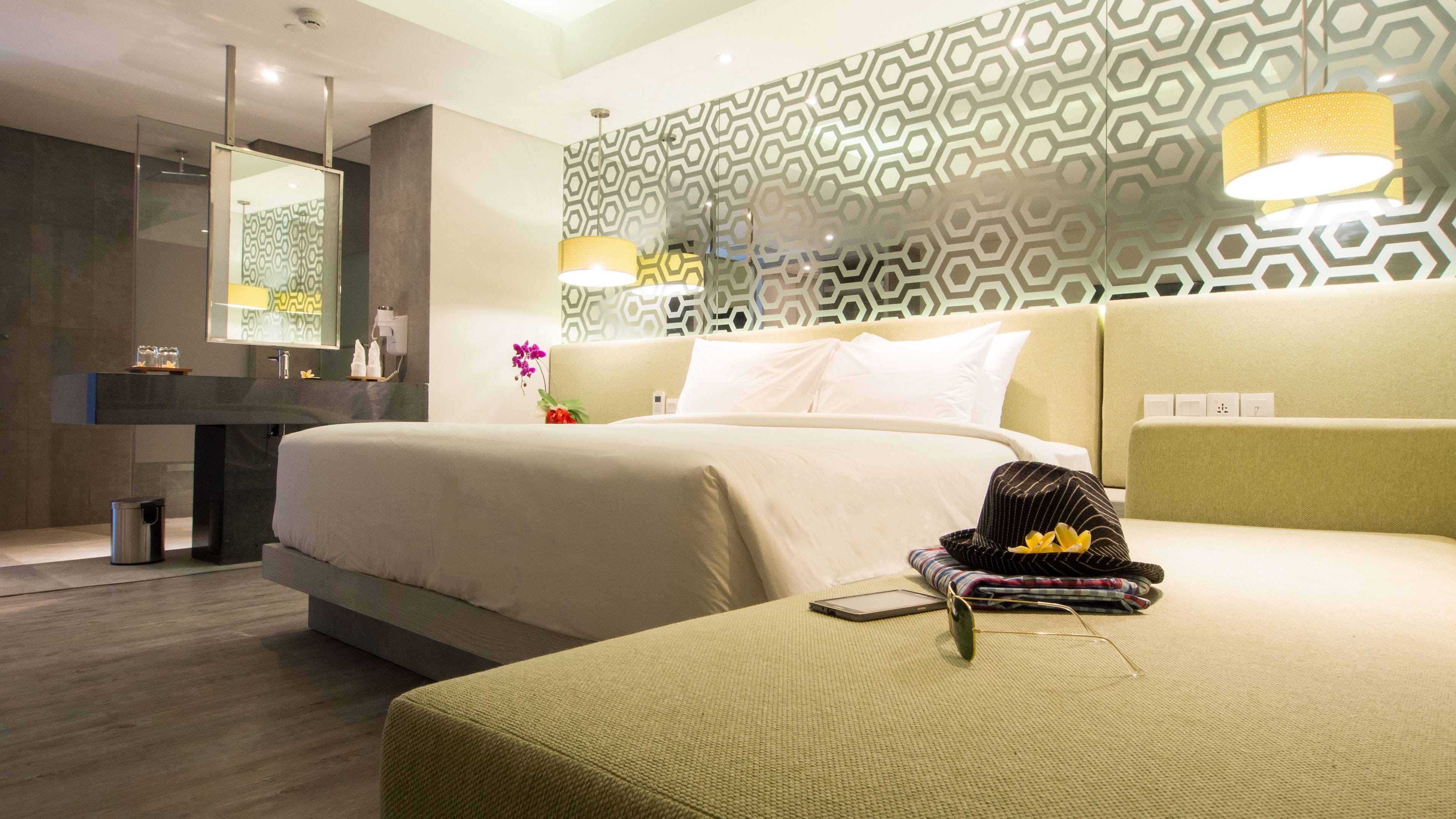 Ein modernes Hotelzimmer mit einem großen Bett, einem Nachttisch, einem Spiegel und einer Wand mit Muster.