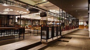 A spacious indoor area with a long counter, wooden flooring, and a modern design with exposed ceilings and lighting fixtures. - Daun Bali Seminyak Hotel (Keroboken Kelod)