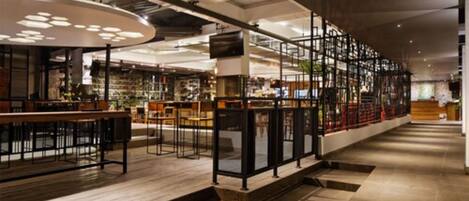 Un vaste espace intérieur doté d’un long comptoir, de planchers en bois et d’un design moderne, avec des plafonds apparents et des luminaires originaux.