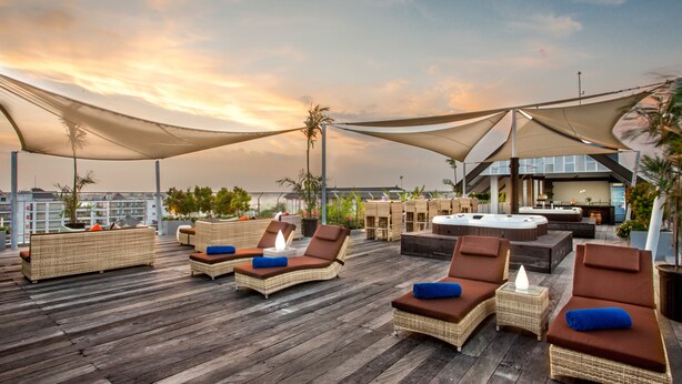 A rooftop lounge with wicker furniture, a hot tub, and a bar area.