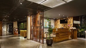 A modern reception area with a wooden reception desk, a large potted plant, and a checkered wall design.