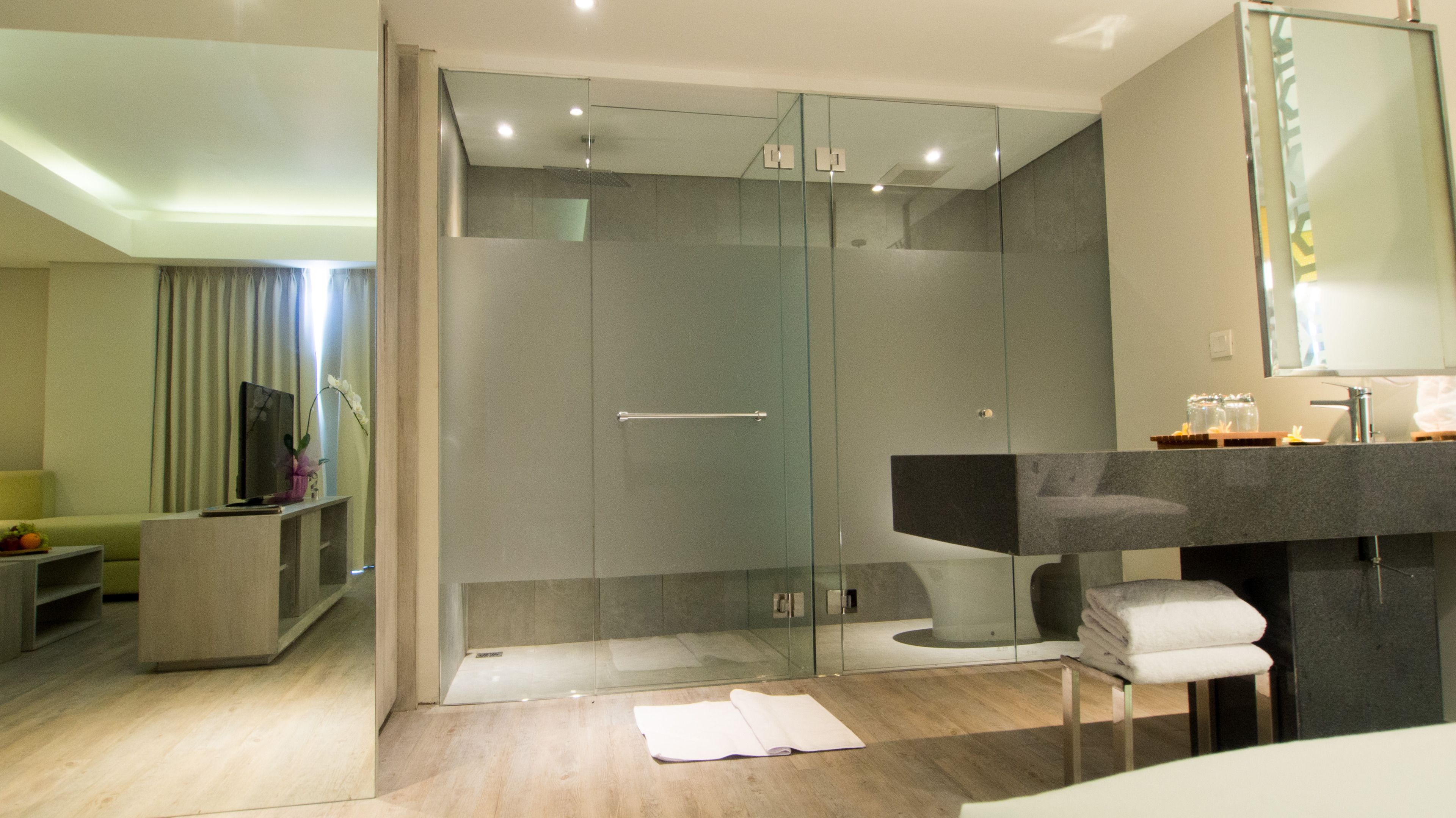 Un baño moderno con ducha de vidrio, lavamanos con encimera de mármol y espejo sobre el lavamanos.