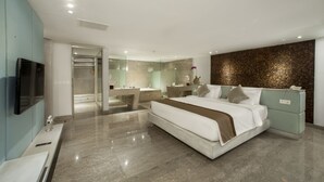 A modern hotel room with a large bed, a vanity with a mirror, a bathtub, and a seating area with a small table and chairs.