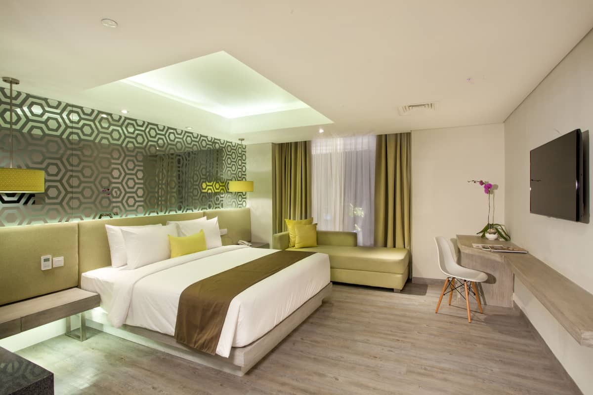 Una habitación de hotel moderna con una cama grande, un escritorio, una silla y un televisor.