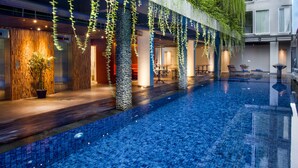 A hotel with a swimming pool, indoor plants, and a modern design.