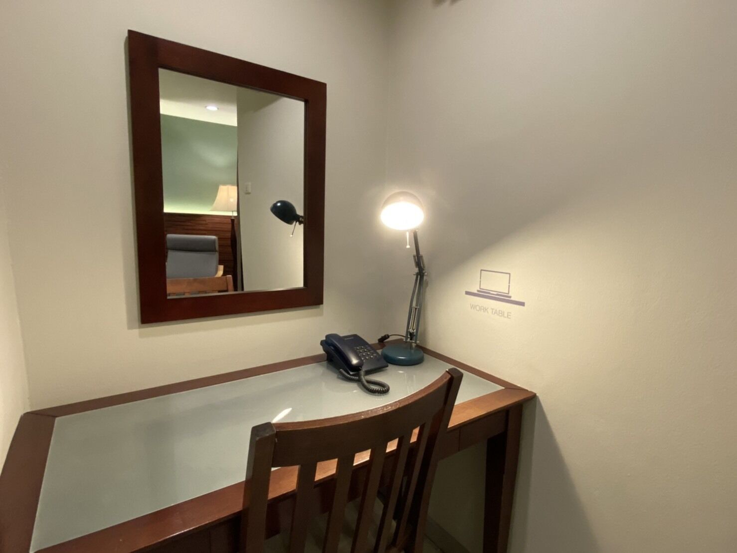 Una scrivania con telefono, lampada da tavolo e specchio.