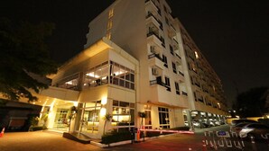 Een hotel met meerdere verdiepingen, een restaurant op de begane grond en een parkeerplaats.