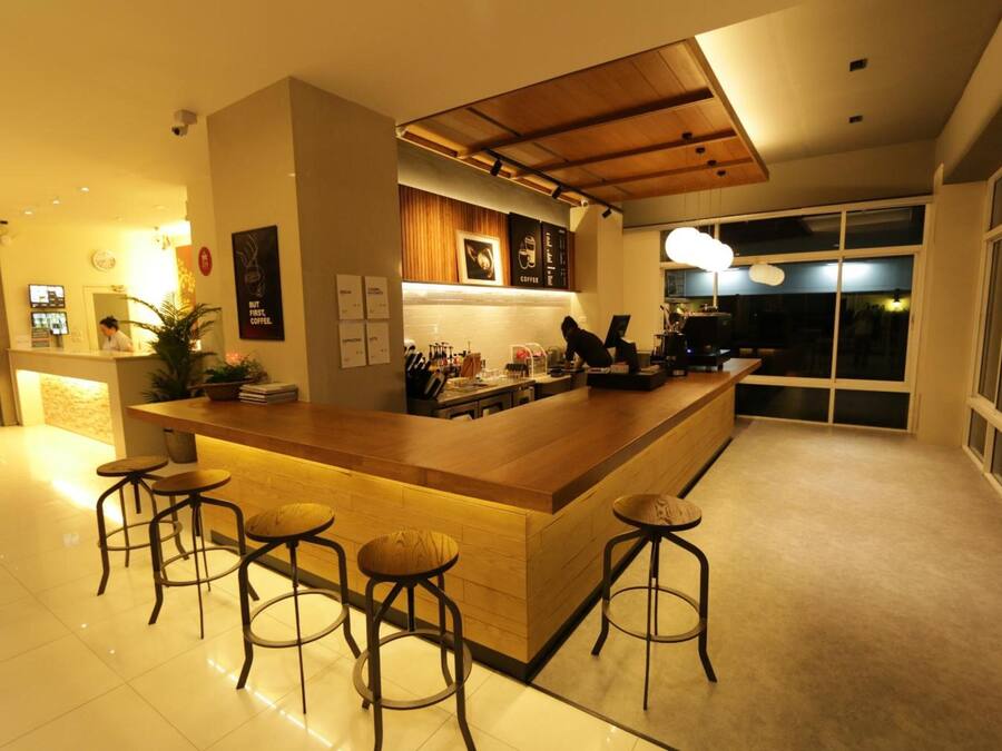A modern kitchen with a central island, bar stools, and a large window offering a view of the outdoors.