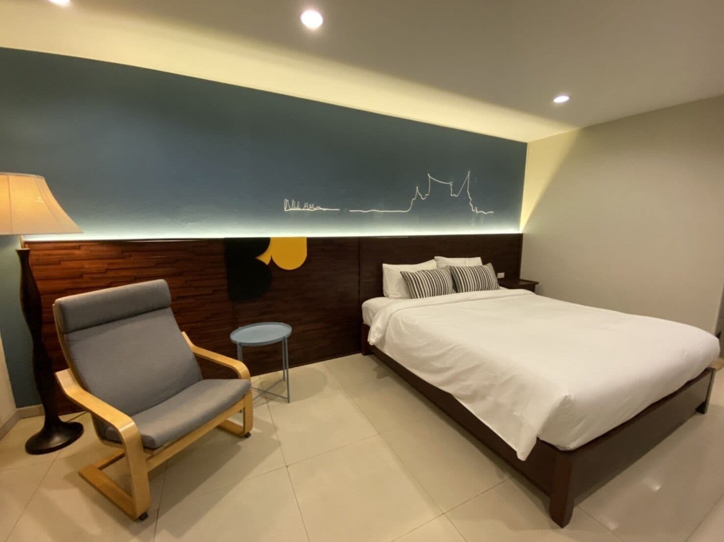 Een moderne hotelkamer met een bed, een stoel en een tafeltje.