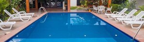 Una piscina al aire libre, sillones reclinables de piscina