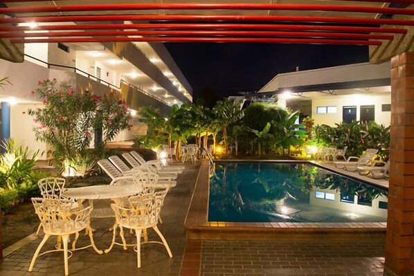 Una piscina al aire libre, sillones reclinables de piscina