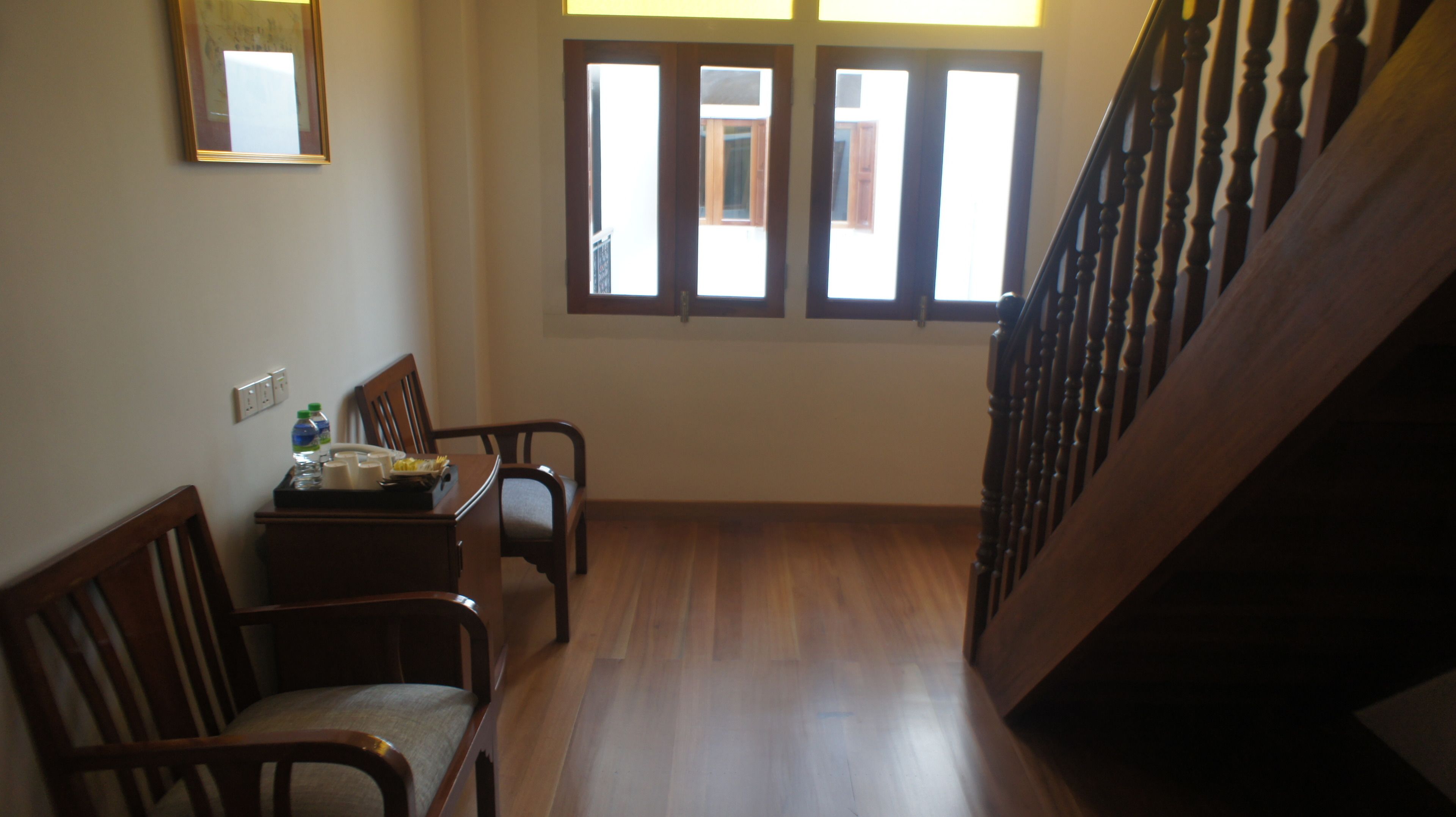 Ein Flur mit Holzboden, einem Esstisch mit Stühlen, einem Spiegel an der Wand und einer Treppe mit hölzernen Geländern.