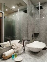 A modern bathroom with a large mirror, two sinks, and a glass shower enclosure.