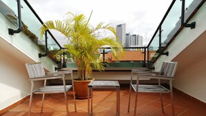 Un balcón con dos sillas, una mesa y una planta en maceta.
