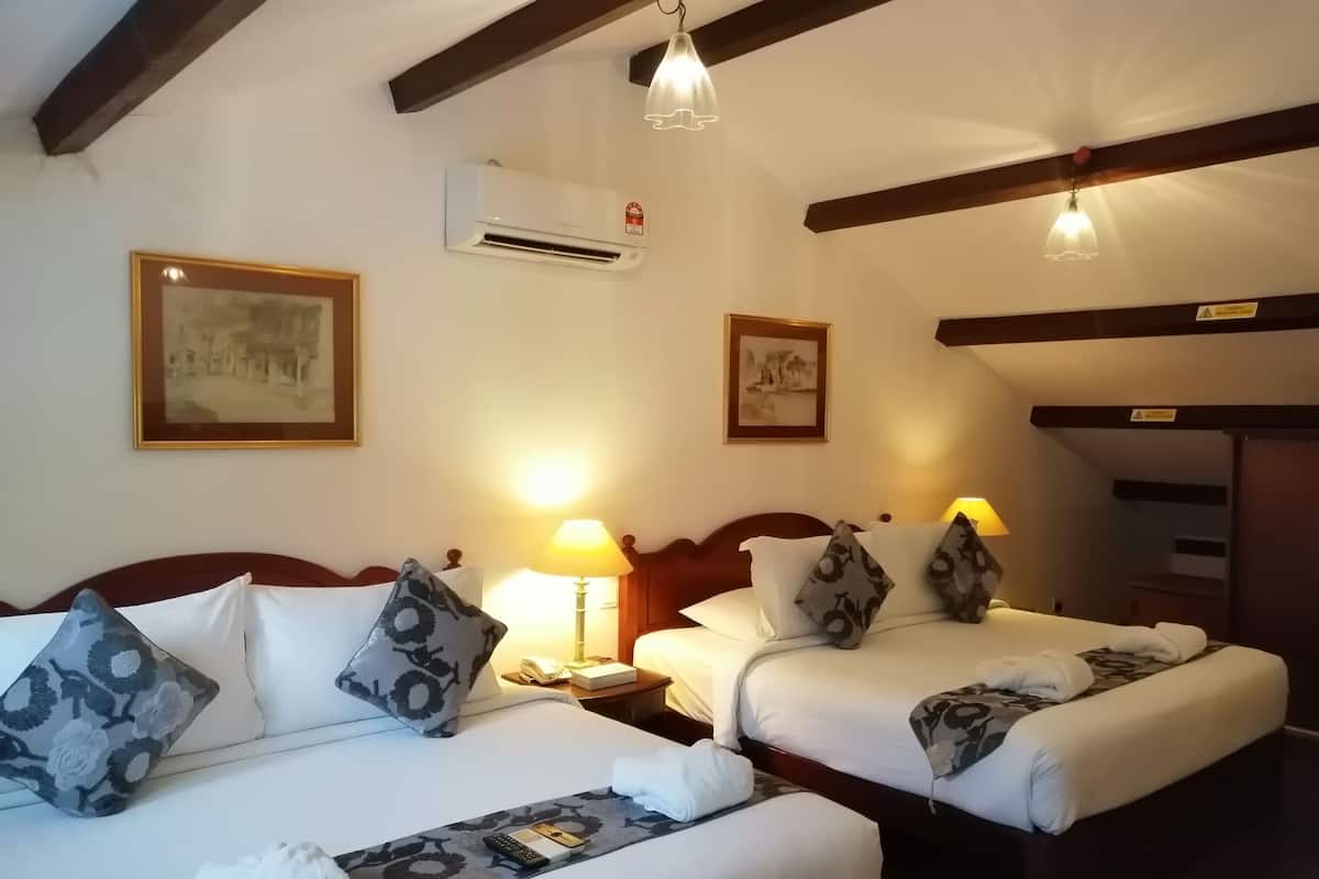 Une chambre d’hôtel avec deux lits, une table de chevet avec une lampe, un appareil de climatisation et des tableaux encadrés aux murs.