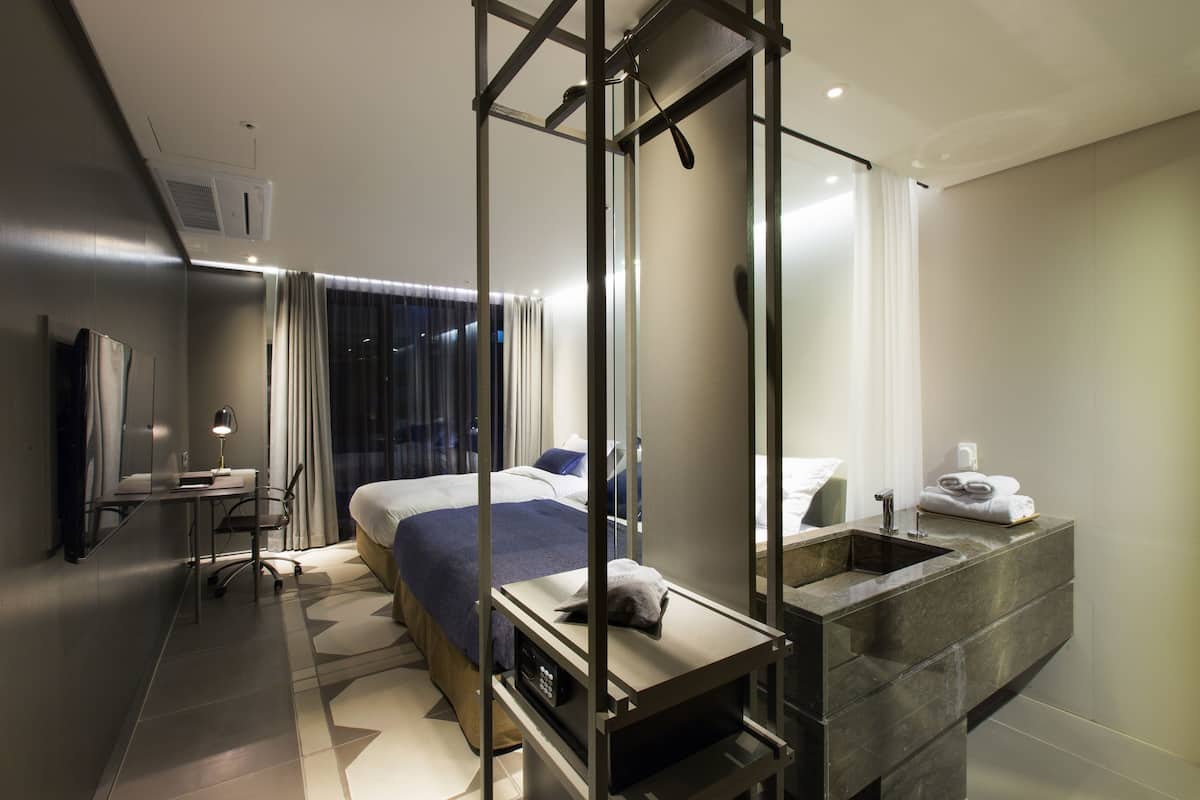A modern hotel room with a bed, desk, and bathroom.
