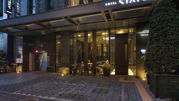 A modern hotel entrance with a glass facade, a sign reading "HOTEL STAY," and potted plants outside. - Stay Hotel Gangnam (Seoul)