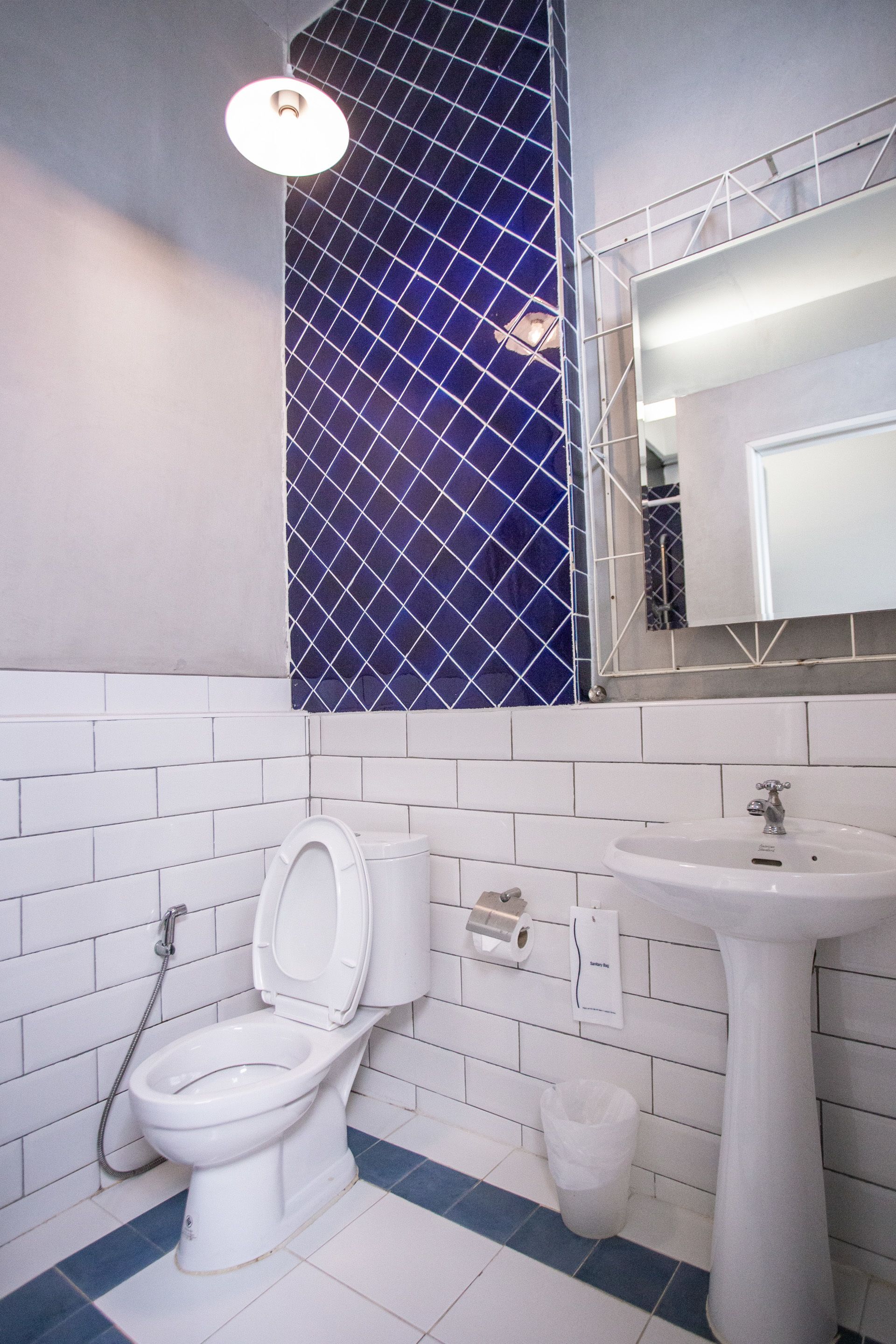Un baño con inodoro, lavamanos y una pared de azulejos azules.