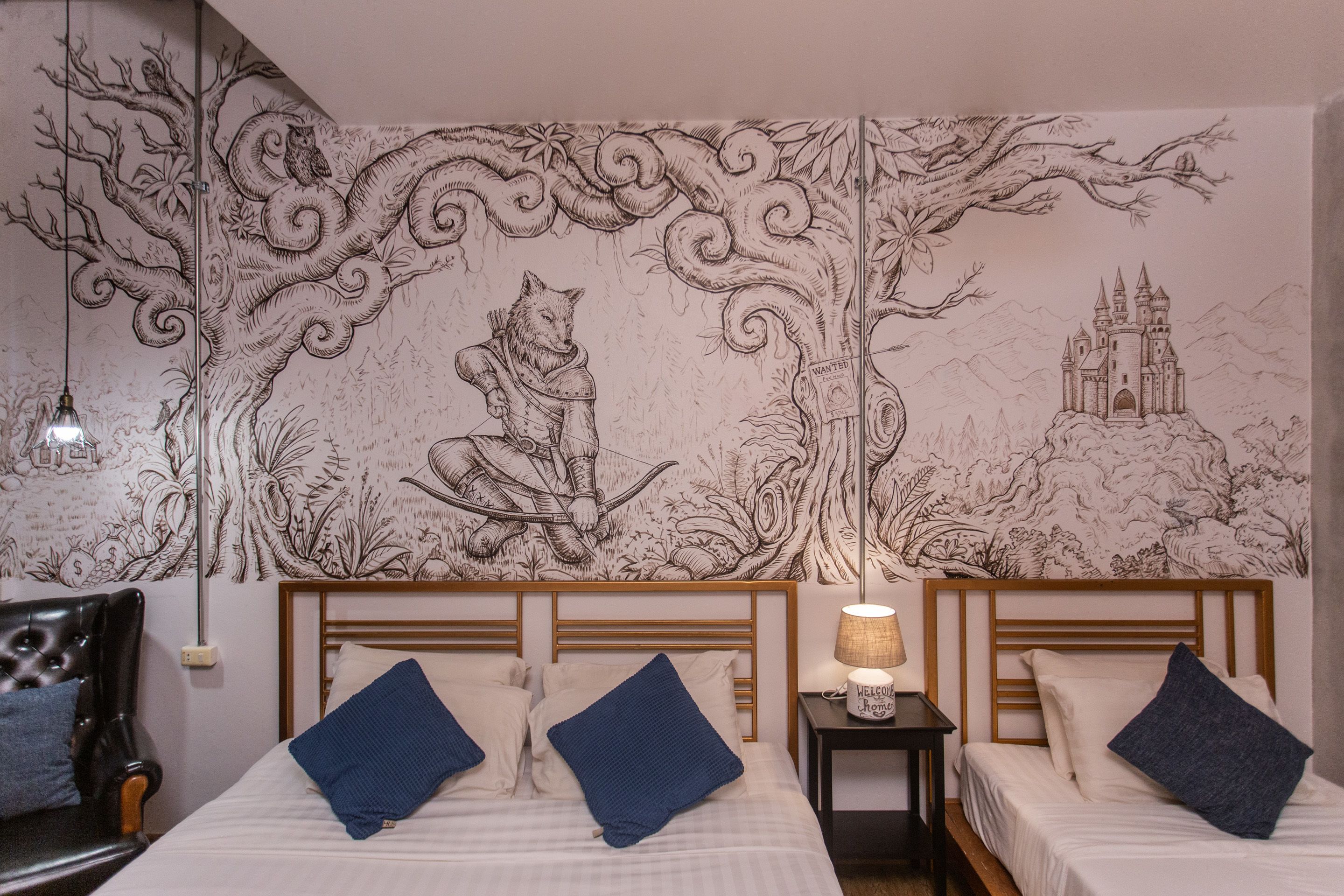 Una habitación con dos camas, un cabecero de madera, una mesita de noche con lámpara y un mural en la pared.