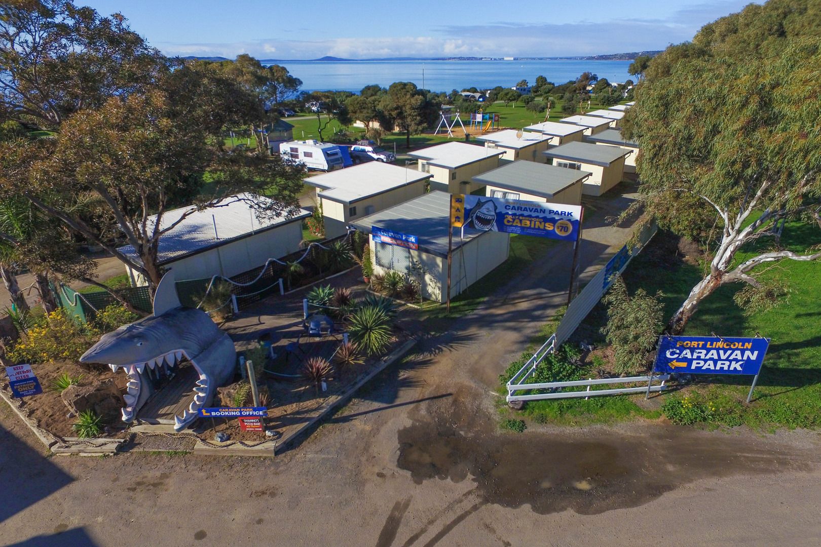 A caravan park with multiple caravan sites, a booking office, and a sign indicating the direction to Fort Lincoln Caravan Park.