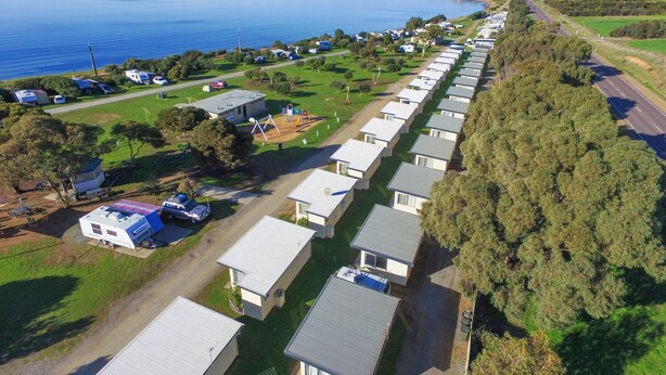 Un parque para caravanas con filas de caravanas y viviendas móviles junto a un lago.