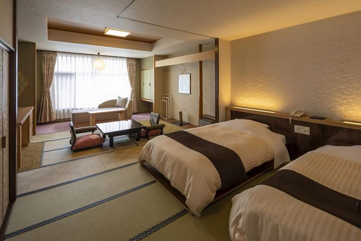 Une chambre d’hôtel avec deux lits, un canapé, une petite table et une vue sur la ville.