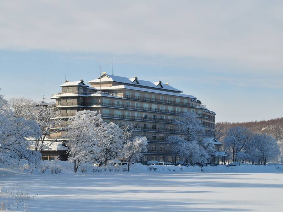 Un hotel de varios pisos con un estilo arquitectónico tradicional, que cuenta con balcones y un paisaje cubierto de nieve.